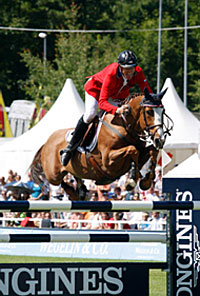 Flexible, a fiery chestnut stallion with a distinctive white blaze, propels rider Rich Fellers over an oxer at St. Gallen, Switzerland.