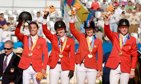 The US Team shines in their nation's red coats as they stand on the podium to receive their gold medals.