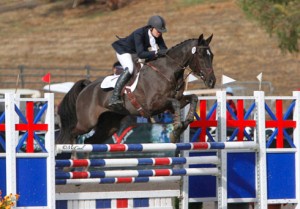 Amber Levine and the bay Anglo Arabian horse Oz Poof of Purchase sail over a red, white and blue jump.