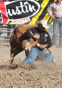 Cowboy Luke Branquinho wrestles a steer to the ground by the horns.