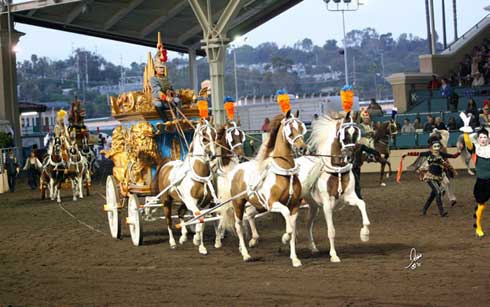 A regal carriage of gold pulled by four high-stepping Paint horses.