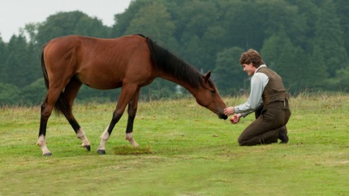 WarHorse_16x9 Actor Jeremy Irvine feeds his horse Joey in a field.