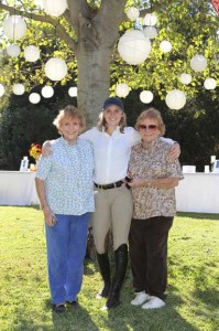 Three women under lantern-festooned tree.