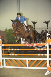 Francie Steinwedell-Carvin cuts a pretty picture in her royal blue blazer sailing over a bright orange jump.