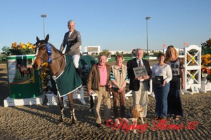 Rich Fellers astride blanketed horse accepts victory trophy.