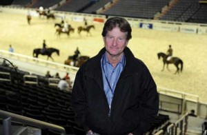 Robert Ridland in an indoor stadium with horses in the deep background.