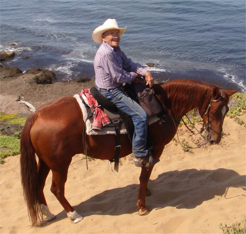 Bert Bonnett astride his chestnut mare at the ocean's edge.