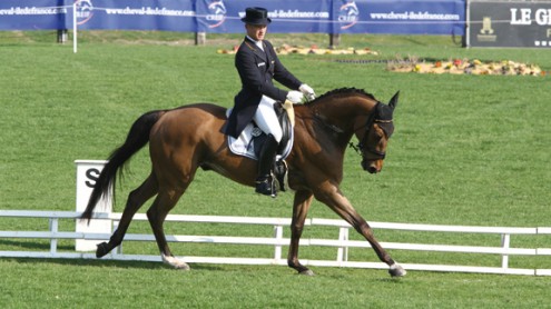 Germany's Michael Jung rides his horse in a dressage test on lush green grass.