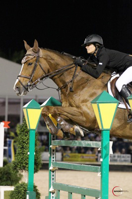 Reed Kessler and her horse clear a jump designed as two green streetlamps.