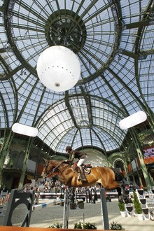 Horse jumping, spectacularly framed against the ornate metal-and-glass roof of Paris' Grand Palais.