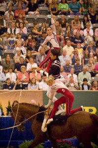 Pyramid of three people on the back of a horse, vaulting.