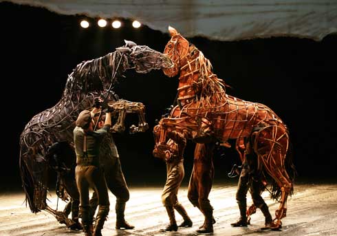 Actors manipulate life-sized horse puppets on the London stage.