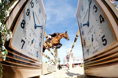 Horse seen jumping between two giant timepieces.