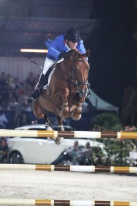 In a sporty blue jacket, Gerco Schröder and his bay horse Eurocommerce sail over a vertical jump and directly into the camera lens.