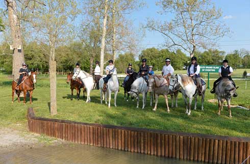 Journalists ride trail horses on the Rolex cross country eventing course.