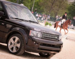 Black Range Rover with horse riding dressage in the background.