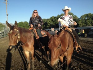 Two women on mules, one holding a dog.