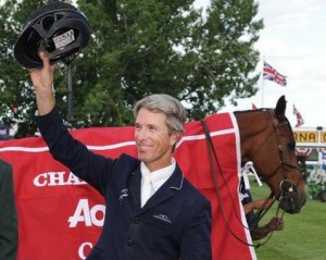 Richard Spooner hoists his helmet in front of his horse, in a crimson cooler.