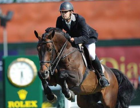 Egyptian rider Nayel Nassar pilots his bay horse over a jump as a Rolex timekeepers clock ticks off the seconds in the background.