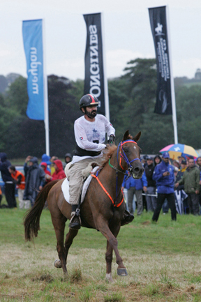 Sheikh Mohammed Bin Rashid Al Maktoum rides his horse across the finish line in the rain.