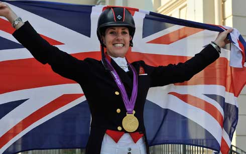 Charlotte Dujardin, individual dressage gold medalists, poses before her nation's British flag.