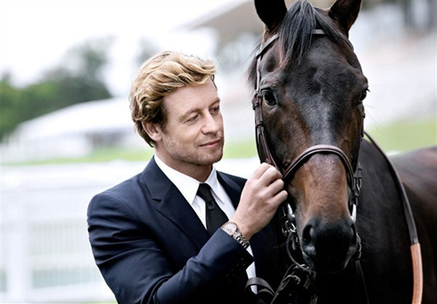 Actor Simon Baker shows off his watch, posing with a horse.