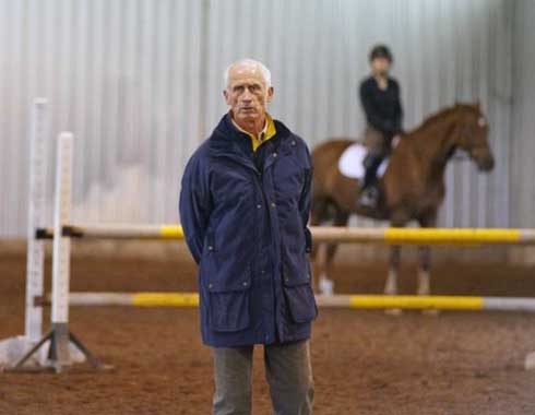 Olympian Joe Fargis strikes a pose in front of a vertical with horse and rider.