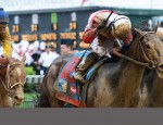 Jockey Joel Rosario raises his crop in victory as a mud-splattered Orb crosses the finish line at the Kentucky Derby.