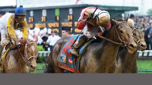Jockey Joel Rosario raises his crop in victory as a mud-splattered Orb crosses the finish line at the Kentucky Derby.