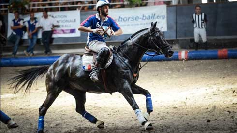 French horseball player Benjamin Depons rides without reins, clutching the ball in both hands.