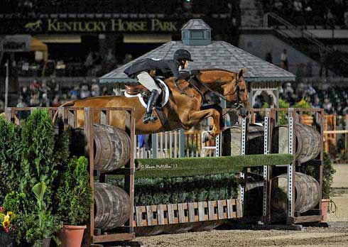 Liza Boyd and Brunello jump a lovely grass-covered hunter obstacle.