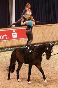 Equestrian vaulters Kimberly and Cassidy Palmer do gymnastics on their horse's back.