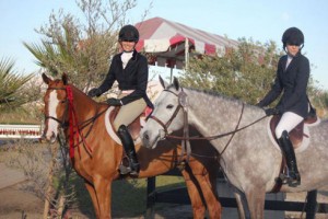 Hope Glynn and Erin Bland astride their hunter horses in a HITS arena.