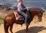 Bert Bonnett astride his chestnut mare at the ocean's edge.