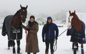 Eventing riders smile with their horses in front of Southern California landscape blanketed with snow.