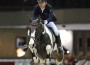 Piebald horse leaping over a jump.