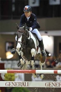 Piebald horse leaping over a vertical jump.