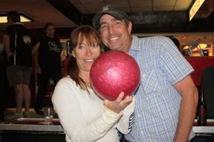 Couple pose with a red bowling ball.