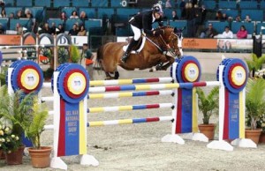 Rich Fellers and Flexible soar over an appropriately themed "championship ribbon" jump