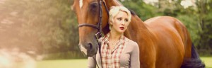 Girl in plaid Le Fash blouse stands beside her chestnut horse.