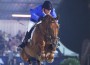 In a sporty blue jacket, Gerco Schröder and his bay horse Eurocommerce sail over a vertical jump and directly into the camera lens.