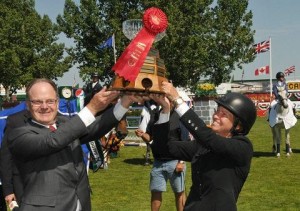 USA rider Elizabeth "Beezie" Madden seen hoisting her trophy, adorned with red ribbon, with Atco Power president John Eli.