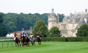 Horses racing on turf at Chantilly with Chateau de Chantilly in background