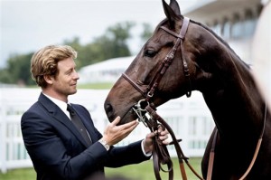 Actor Simon Baker poses with a Thoroughbred race horse.