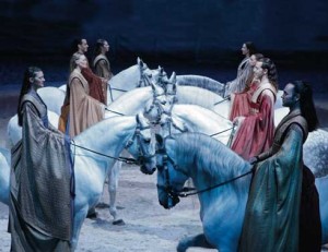 Cavalia performers form two rows of white horses.