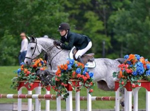 Youngster Lillie Keenan and her grey horse sail over a beautifully decorated oxer.