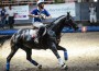 French horseball player rides without reins, clutching the ball in both hands.